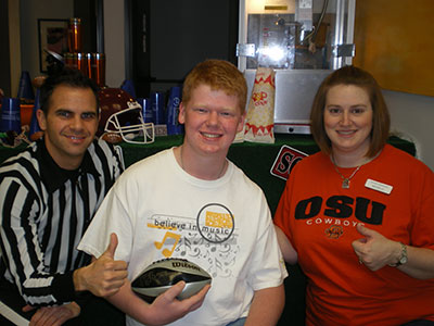 Three people posing together indoors, holding food items, casual setting.