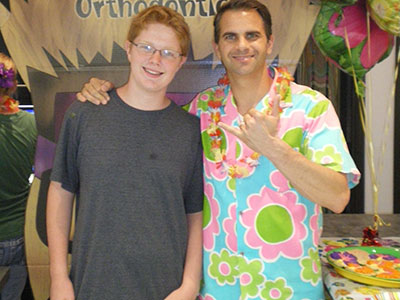 Two men posing together at Emerson Orthodontics event with colorful decorations in background.