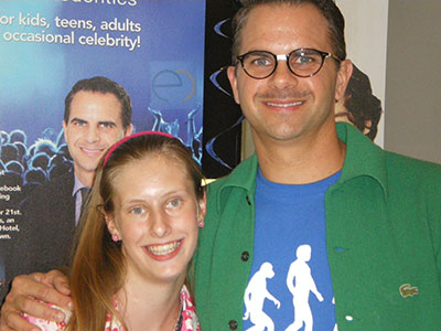 Two people smiling at camera at orthodontics event with promotional banner in background.