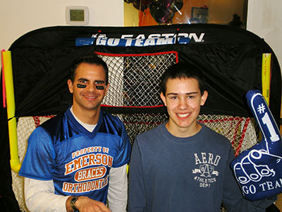 Two young men posing together inside a basketball hoop structure at Emerson Orthodontics.