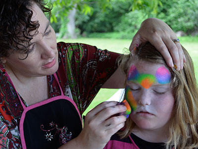 Two children with face paint applied outdoors in natural daylight setting.