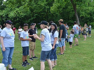 Group of people wearing light blue shirts participating in outdoor community event in park.