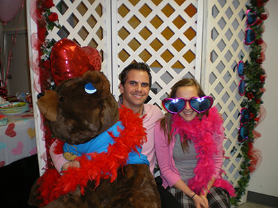 Man and child pose with person in Elmo costume at festive orthodontics office holiday party.