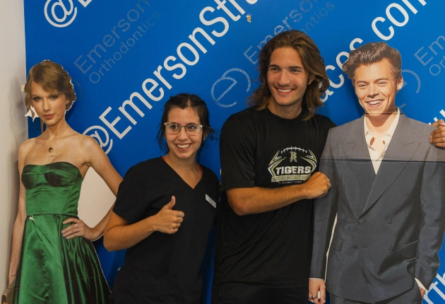 Four people pose together at Emerson Orthodontics event against blue branded backdrop.