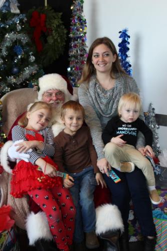 Family portrait with mother and four children in holiday setting with decorated Christmas tree.