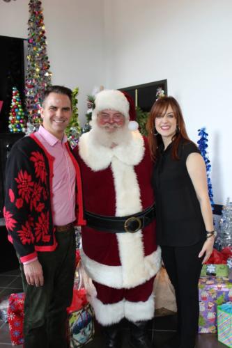 Santa poses with two smiling women at holiday office party celebration.