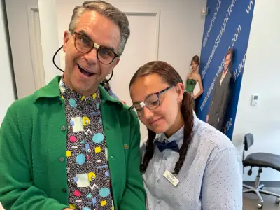 Two people smiling at camera in orthodontic office wearing festive holiday attire.