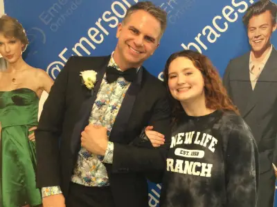 Two people posing together at Emerson Orthodontics event with blue backdrop signage.