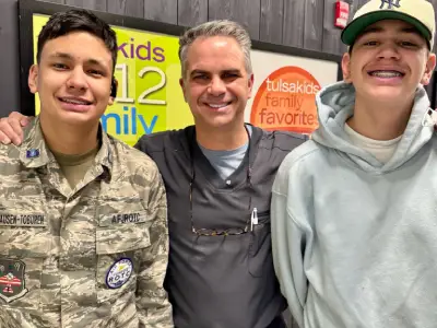 Three men smiling at camera in front of kids activity signage at Emerson Orthodontics office.