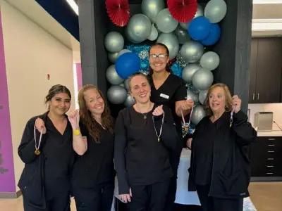 Emerson Orthodontics team members posing together in front of decorative balloons in an office setting.