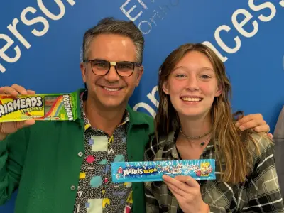 Two people holding Airheads candy at Emerson Orthodontics event with blue branded backdrop.