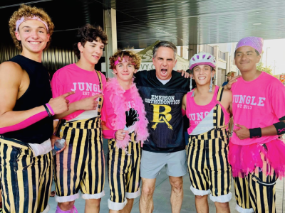 Group of people wearing pink and zebra-striped outfits posing together indoors at an event.