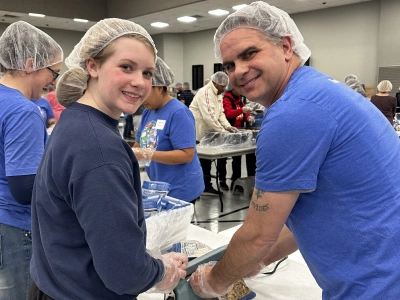 Orthodontist and female staff member smiling while working together in clinical treatment room.