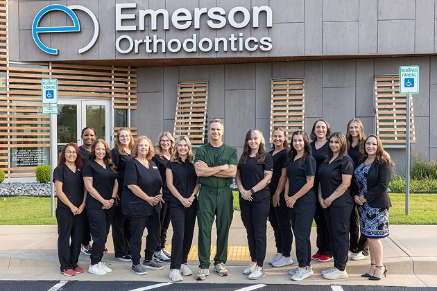 Emerson Orthodontics team members standing together in front of office building entrance.