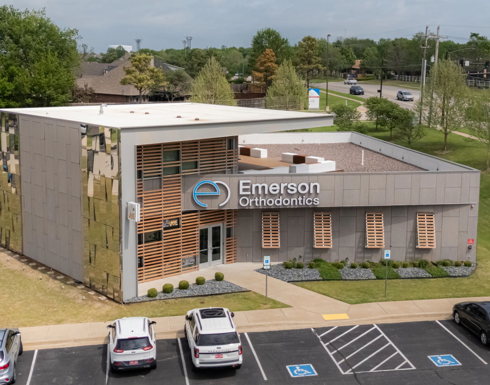 High-angle view of the modern Emerson Orthodontics building exterior, featuring a flat roof, large sign, and parking lot.